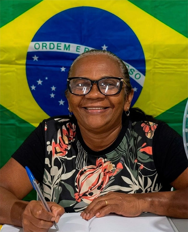 Aluna EJA sorrindo enquanto escreve